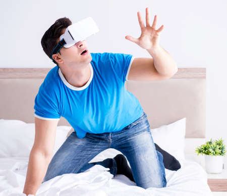Young man in bed wearing a vr virtual reality head set