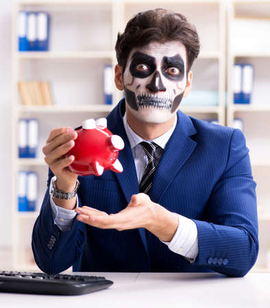 Businessmsn with scary face mask working in officeの写真素材