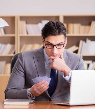 Businessman gambling playing cards at workの写真素材