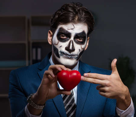 The businessman with scary face mask working late in office