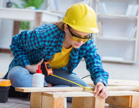 Female repairman carpenter cutting joining wooden planks doing r