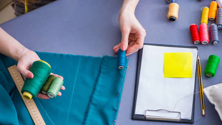 Woman tailor working on a clothing sewing stitching measuring fa