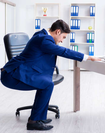 Young businessman doing sports stretching at workplaceの写真素材