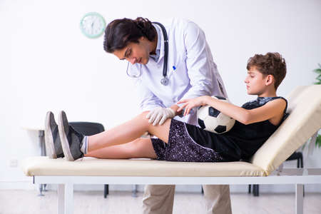 Boy football player visiting young doctor traumatologistの写真素材