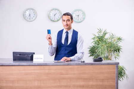 Young man receptionist at the hotel counterの写真素材