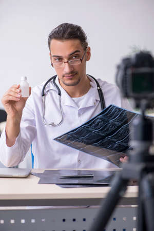 Young male doctor radiologist recording video for his blogの写真素材