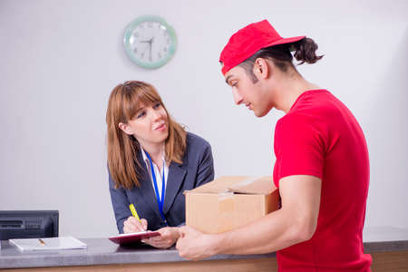 Young male courier delivering box to hotels reception