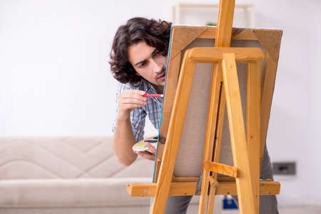 Young handsome man enjoying painting at homeの写真素材