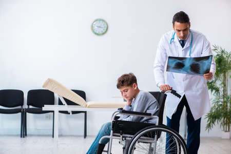 Young male doctor pediatrist and boy in wheel-chairの写真素材