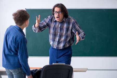 Funny male teacher and boy in the classroomの写真素材