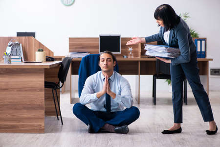 Male employee doing yoga exercises in the officeの写真素材