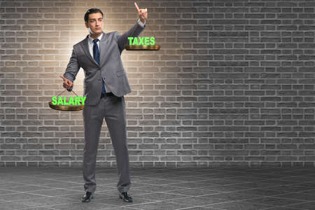 Businessman trying to find balance between taxes and salaryの写真素材