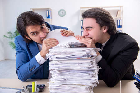 Two male colleagues unhappy with excessive workの写真素材