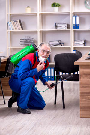 Old professional contractor doing pest control in the officeの写真素材