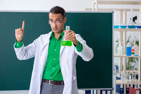 Young male chemist teacher in front of blackboardの写真素材