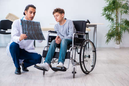 Young male doctor pediatrist and boy in wheel-chairの写真素材