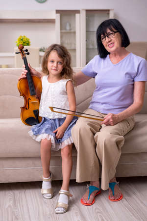 Old lady teaching little girl to play violinの写真素材