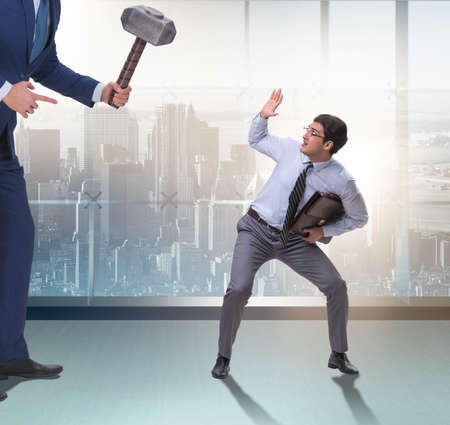 Bad angry boss threatening employee with hammerの写真素材