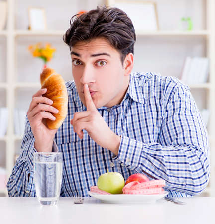 Man having dilemma between healthy food and bread in dietingの写真素材