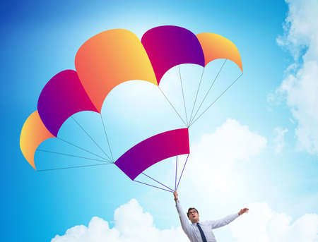 Young businessman falling on parachute in business conceptの写真素材