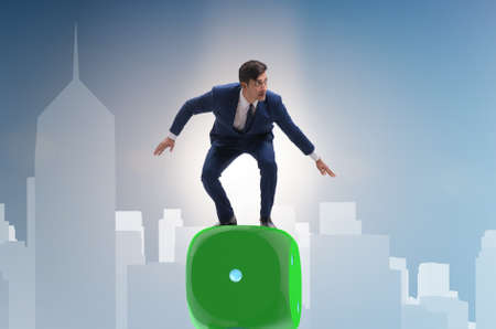 Businessman balancing on top of dice stack in uncertainty conceptの写真素材