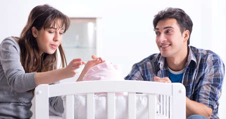 Young parents with their newborn baby near bed cotの写真素材