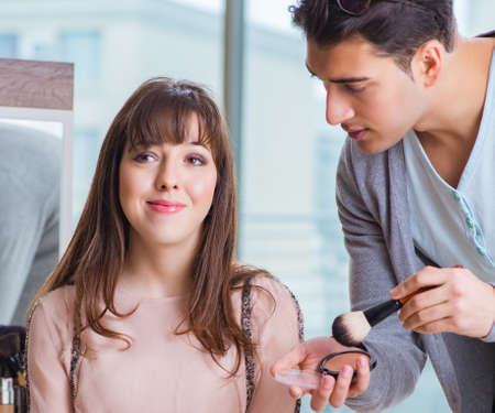 Man doing make-up for cute woman in beauty salonの写真素材