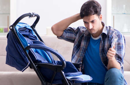 Young father assembling baby pram at homeの写真素材