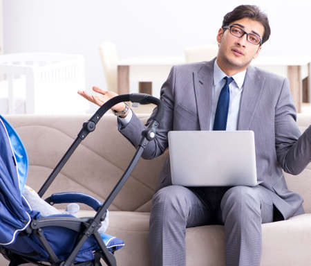 Businessman looking after newborn baby at home and teleworkingの写真素材