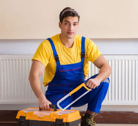 The young repairman contractor repairing heating panelの写真素材