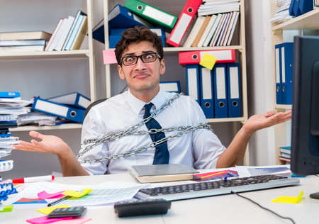Employee attached and chained to his desk with chainの写真素材