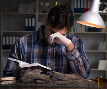 Archeologist working late night in officeの写真素材