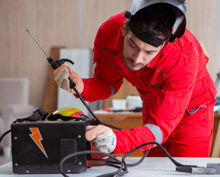 Young repairman with a welding gun electrode and a helmet weldingの写真素材