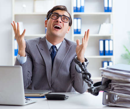 Busy employee chained to his office deskの写真素材