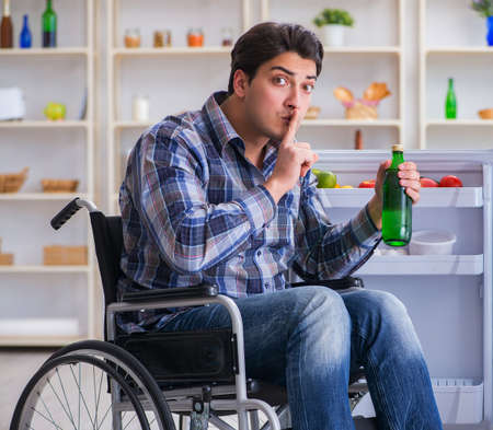 Young disabled injured man opening the fridge doorの写真素材