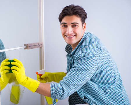 The young man cleaning mirror at home hotelの写真素材