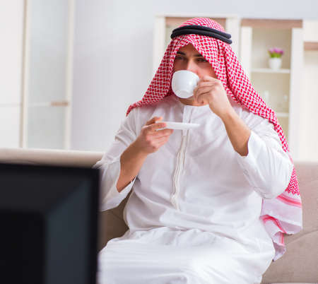 Arab businessman watching tv at homeの写真素材