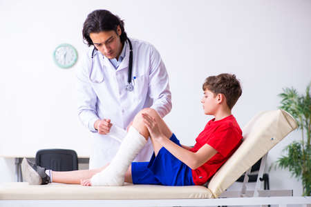 Leg injured boy visiting young doctor traumatologistの写真素材