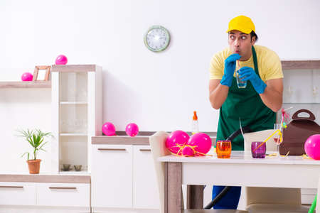 Young male contractor doing housework after partyの写真素材