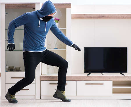 Man burglar stealing tv set from houseの写真素材