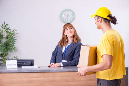Young male courier delivering box to hotels reception