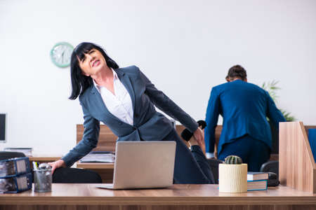 Two employees doing sport exercises in the officeの写真素材
