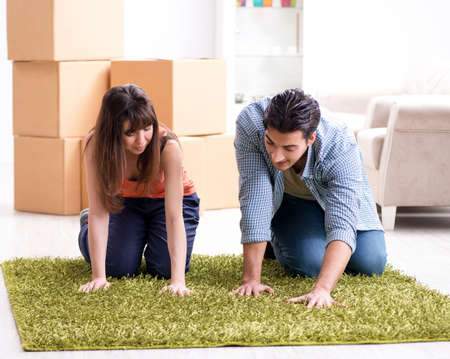 Young family rolling carpet at new apartmentの写真素材