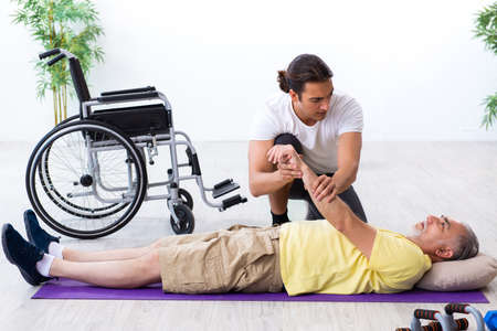 Old injured man doing exercises indoorsの写真素材