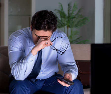 Businessman watching tv at night lateの写真素材