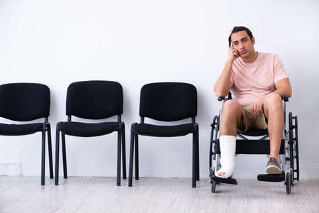 Young injured man waiting for his turn in hospital hallの写真素材