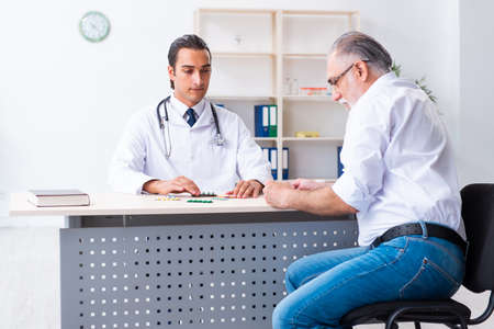 Old man visiting young male doctorの写真素材