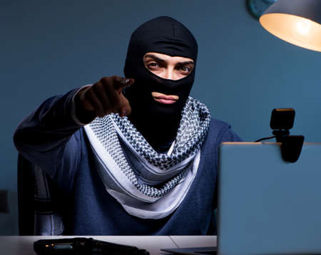 Hacker wearing balaclava mask hacking computerの写真素材