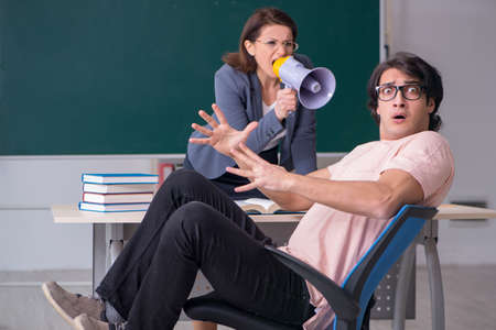 Old female teacher and male student in the classroomの写真素材