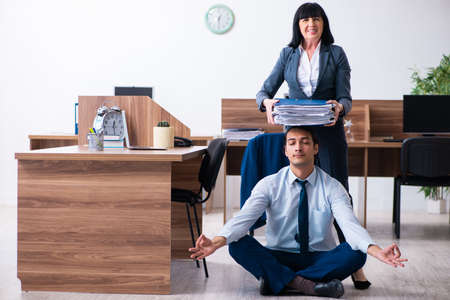 Male employee doing yoga exercises in the officeの写真素材